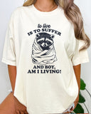 To Live Is To Suffer Shirt in natural color with a cute raccoon graphic