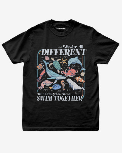 Flat lay of black We Are All Different But In This School We All Swim Together Shirt with cute retro ocean animal design