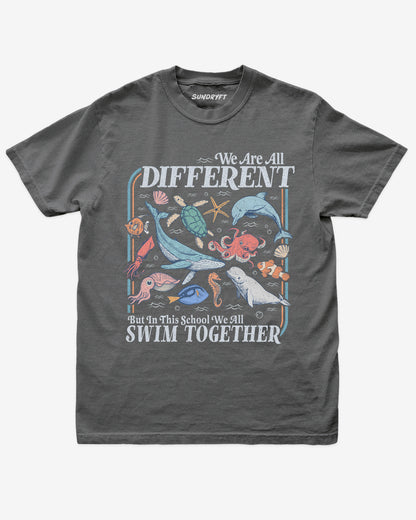 Flat lay of pepper We Are All Different But In This School We All Swim Together Shirt with cute retro ocean animal design