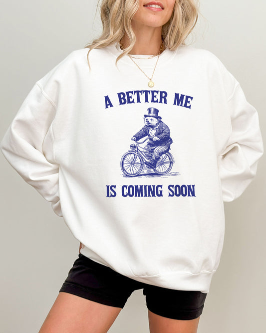 Model wearing white color sweatshirt with 'A Better Me Is Coming' graphic design