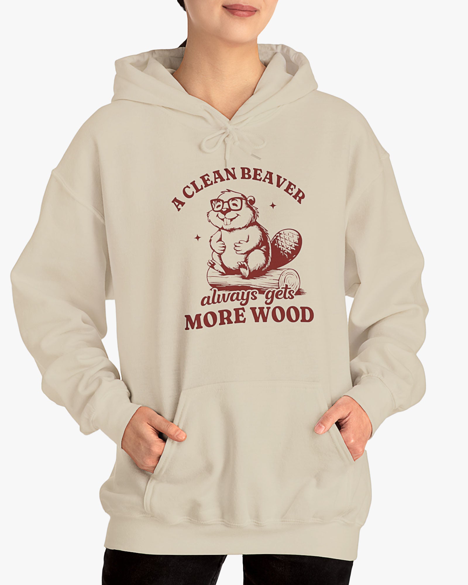 Woman wearing sand beige 'A Clean Beaver Always Gets More Wood' hoodie with funny retro beaver sitting on a wood stump graphic