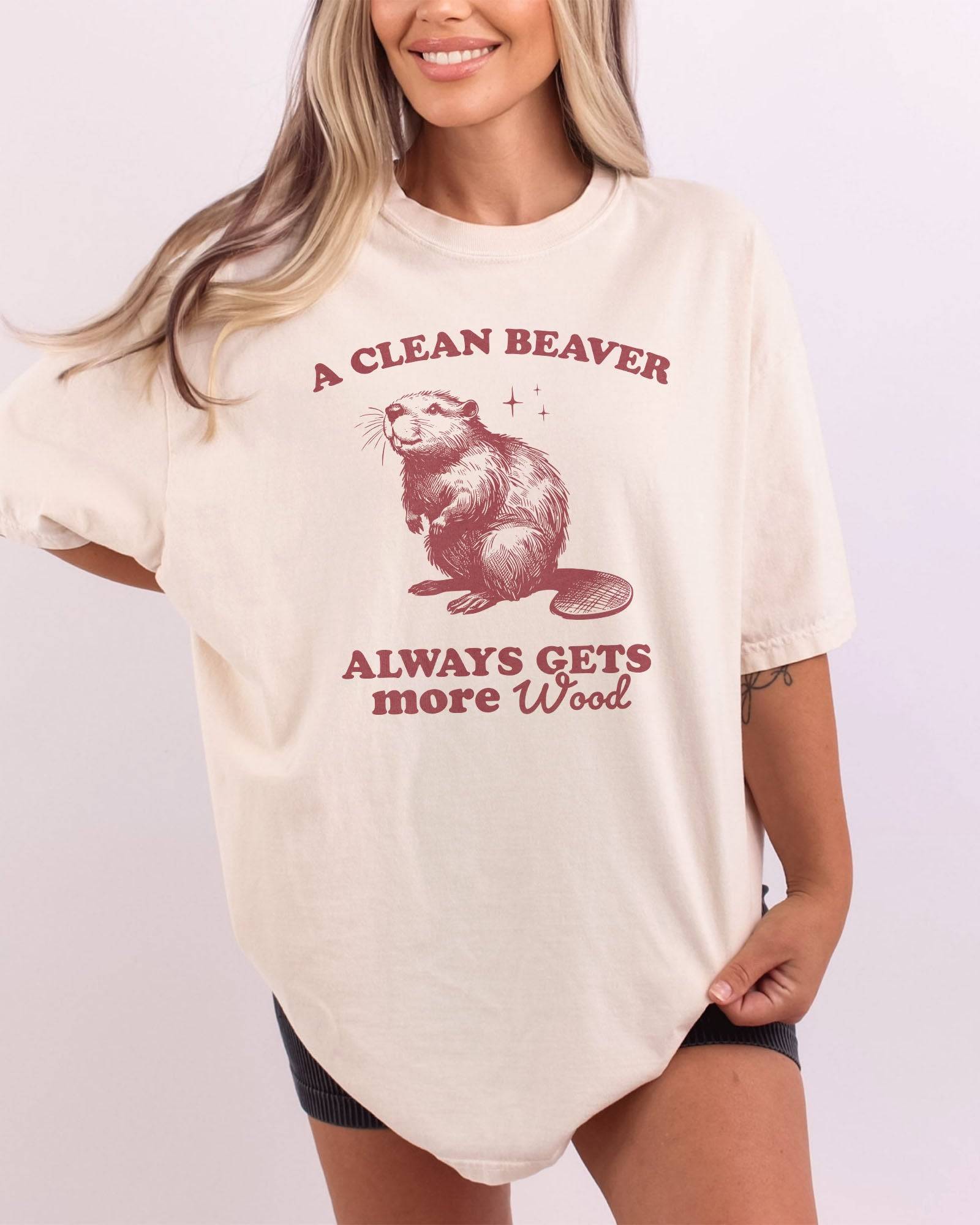 Woman wearing ivory "A Clean Beaver Always Gets More Wood" shirt with funny retro beaver graphic.