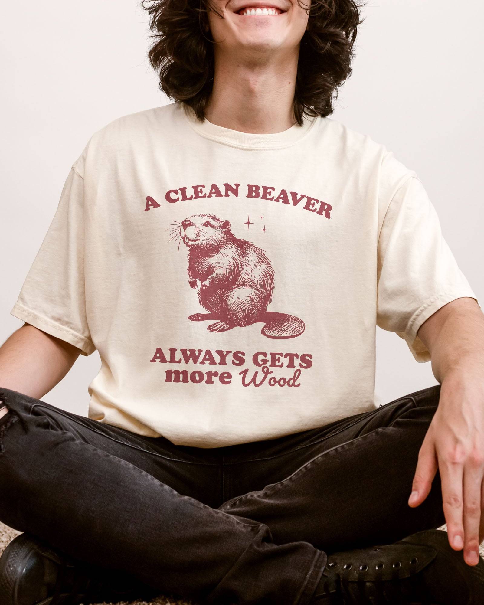 Man wearing ivory "A Clean Beaver Always Gets More Wood" shirt with funny retro beaver graphic.