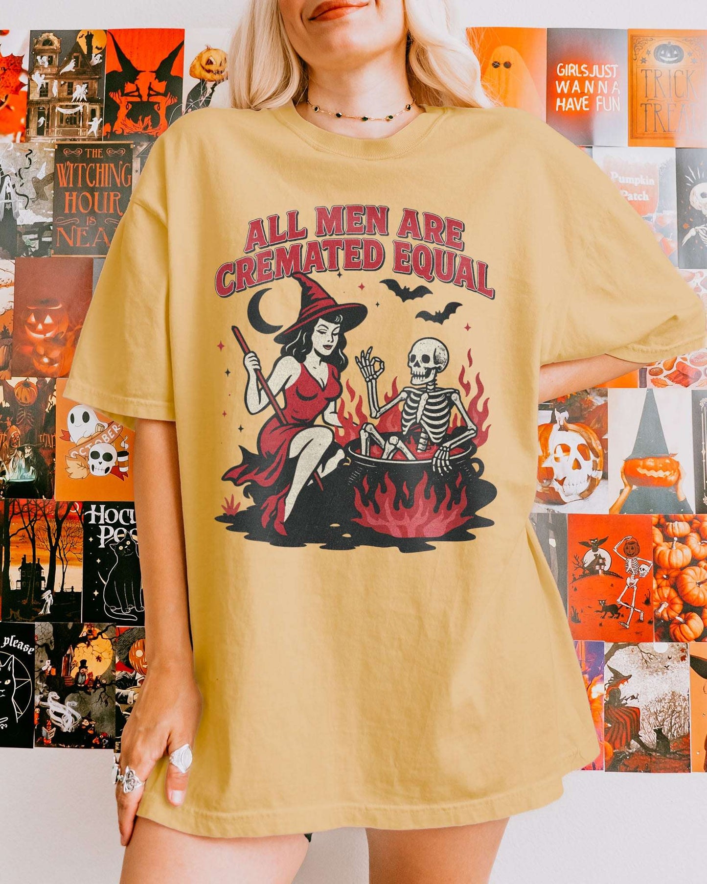 Woman wearing a mustard-colored “All Men Are Cremated Equal” shirt with a retro Halloween graphic of a witch stirring a skeleton in a cauldron.