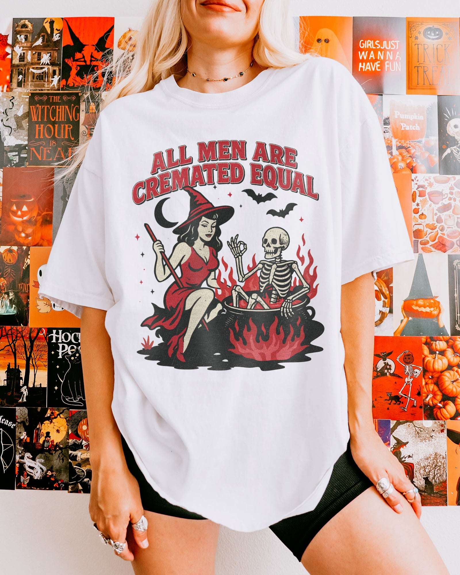 Woman wearing a white-colored “All Men Are Cremated Equal” shirt with a retro Halloween graphic of a witch stirring a skeleton in a cauldron.