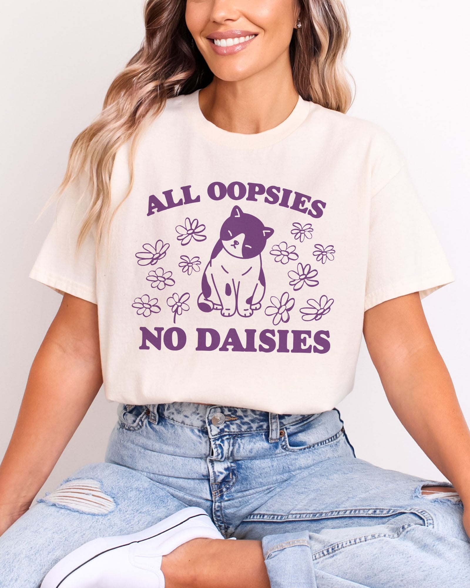 Model wearing natural color shirt with 'All Oopsies No Daisies' graphic design