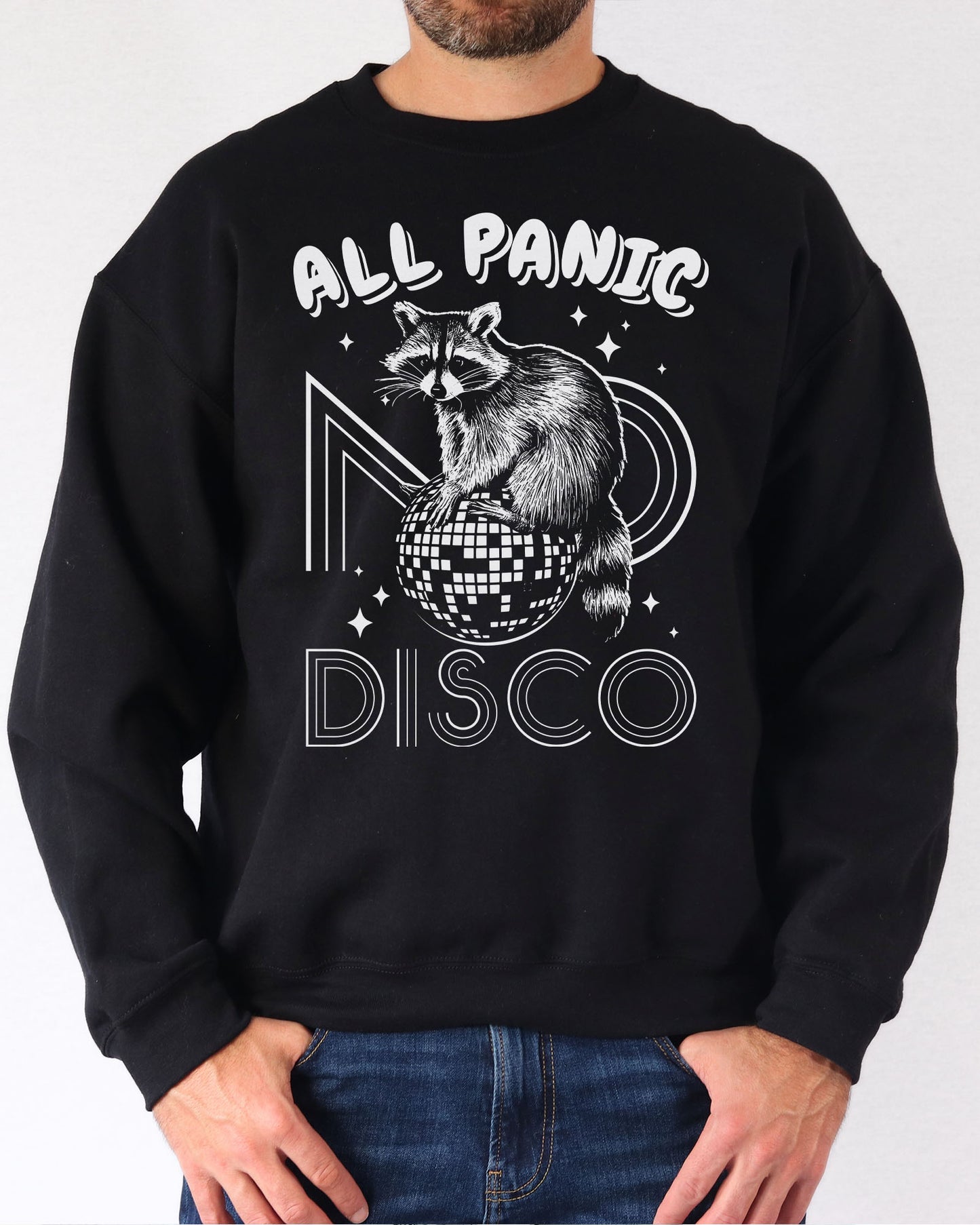 Man wearing a black sweatshirt featuring a funny retro raccoon sitting on a disco ball graphic and the quote 'All Panic No Disco'.