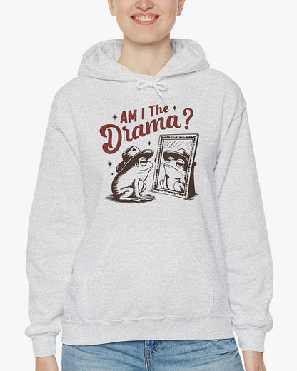 Woman wearing an ash gray 'Am I The Drama?' hoodie featuring a funny retro cowboy frog looking at himself in the mirror graphic.