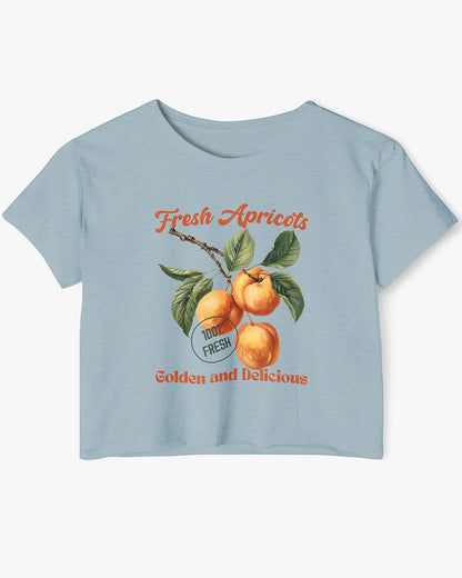Flat-lay stonewash denim crop top featuring a retro apricots fruit graphic in a vintage commercial style.