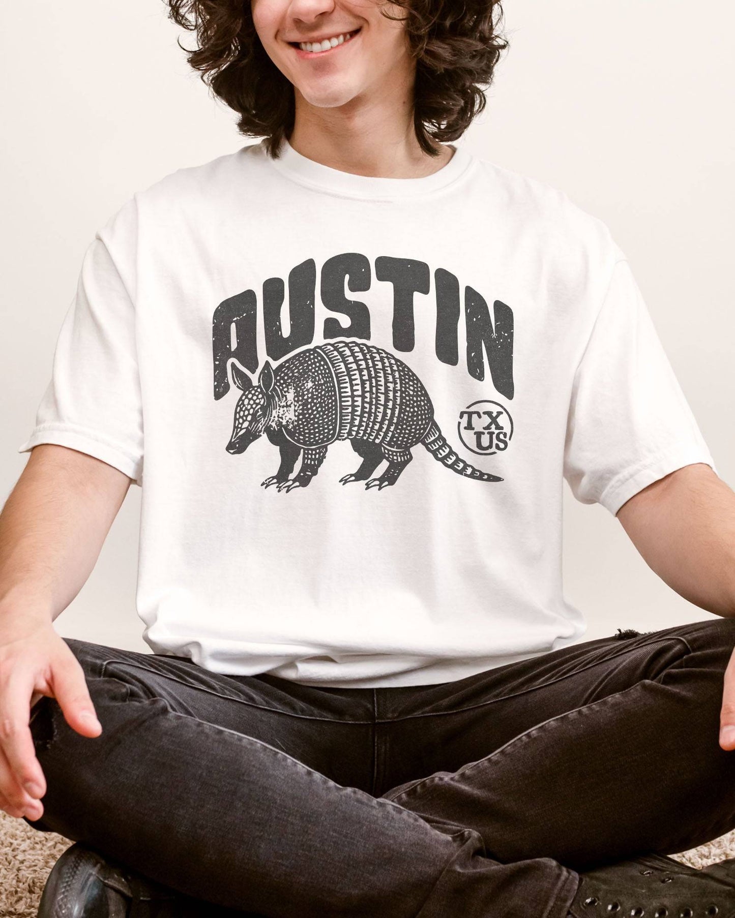 Man wearing "Austin TX US" shirt in white color with retro graphic of an armadillo.