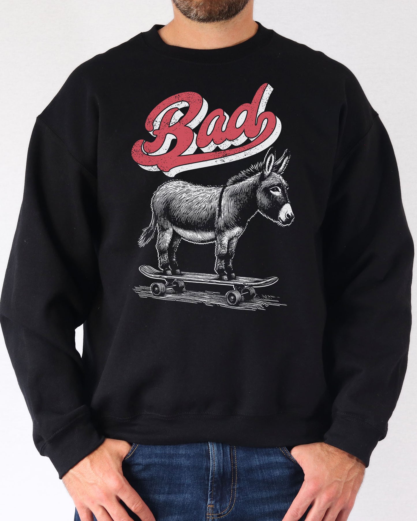 Man wearing a black sweatshirt with a retro graphic of a donkey riding a skateboard and the word 'Bad' above it.