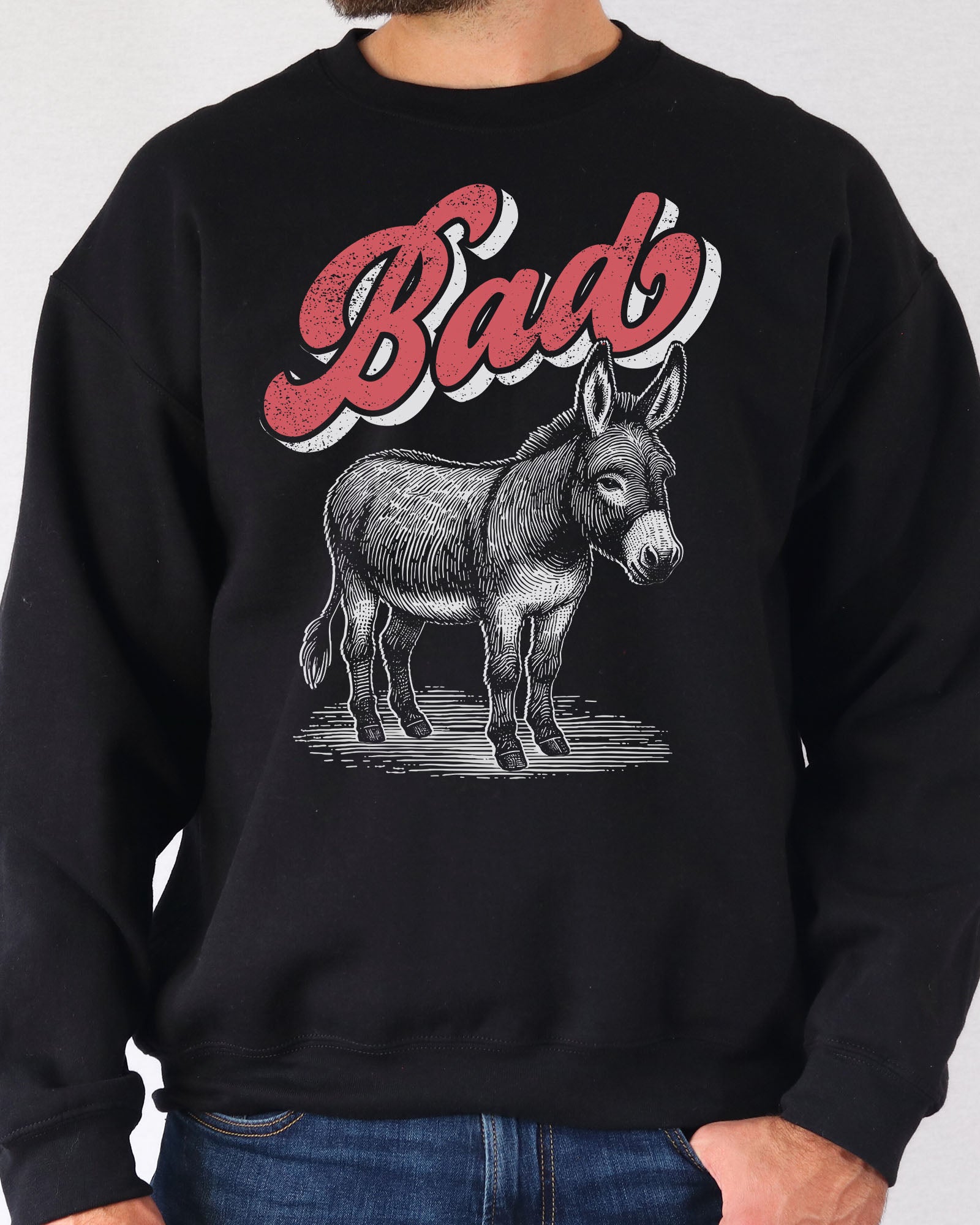 Man wearing a black unisex retro donkey sweatshirt with the word 'Bad' above the graphic.