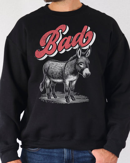 Man wearing a black unisex retro donkey sweatshirt with the word 'Bad' above the graphic.