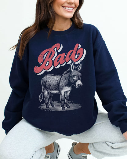 Woman wearing a navy blue unisex retro donkey sweatshirt with the word 'Bad' above the graphic.