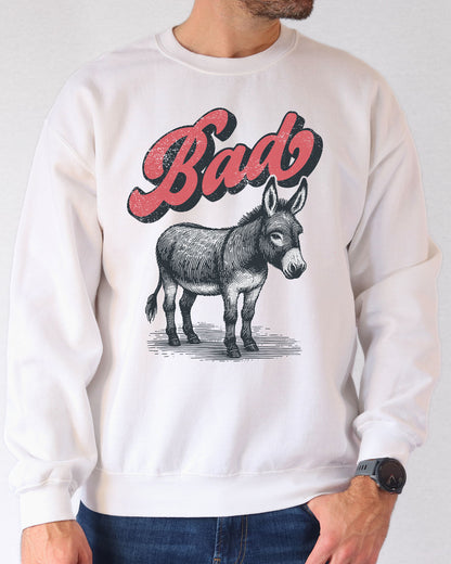 Man wearing a white unisex retro donkey sweatshirt with the word 'Bad' above the graphic.