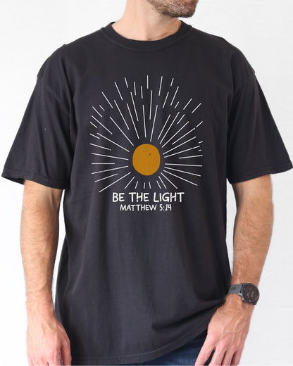Model wearing black color shirt with 'Be The Light - Matthew 5:14' graphic design