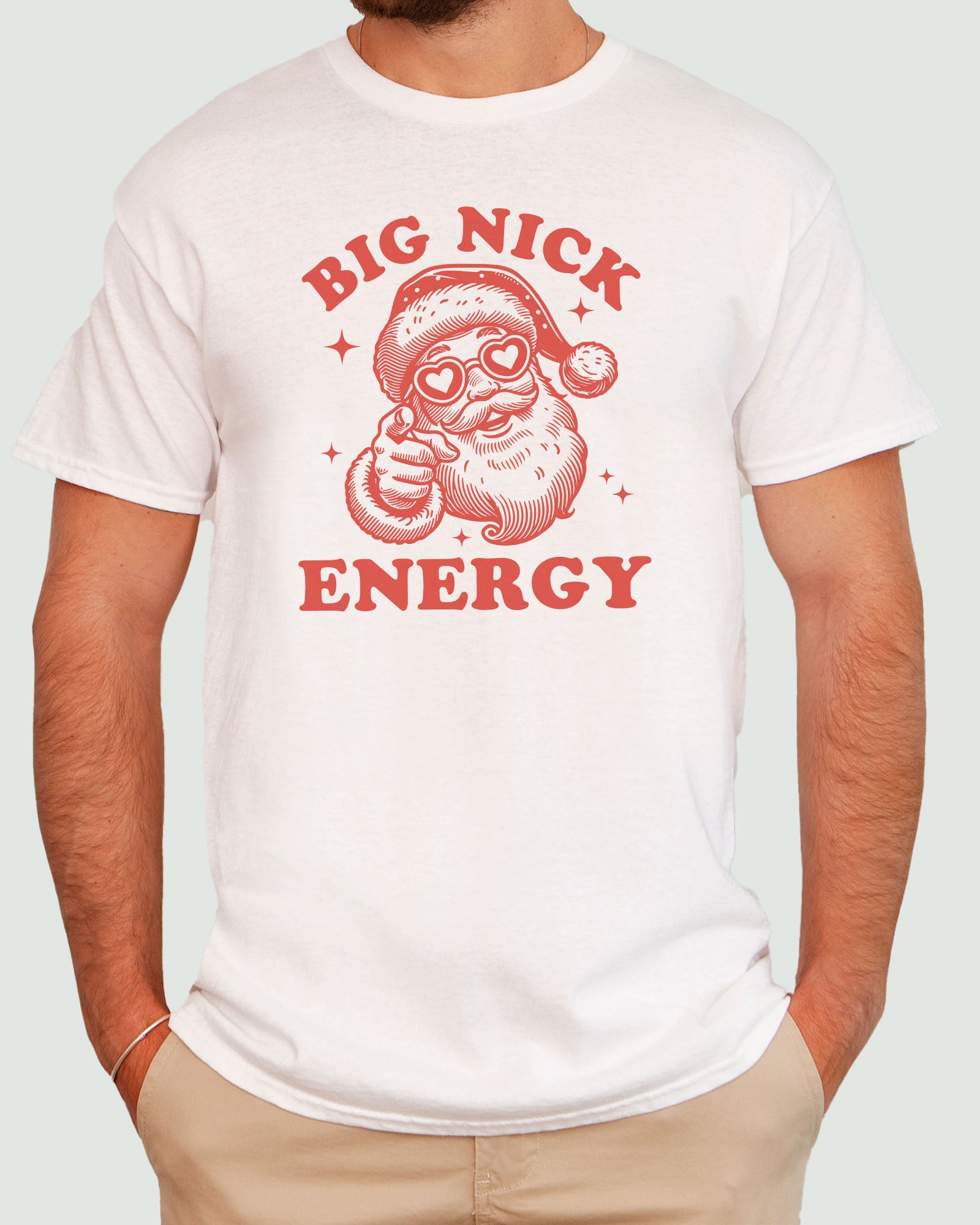 Man wearing a 'Big Nick Energy' shirt in natural beige with a retro Santa Claus graphic and unisex fit, funny Christmas design.