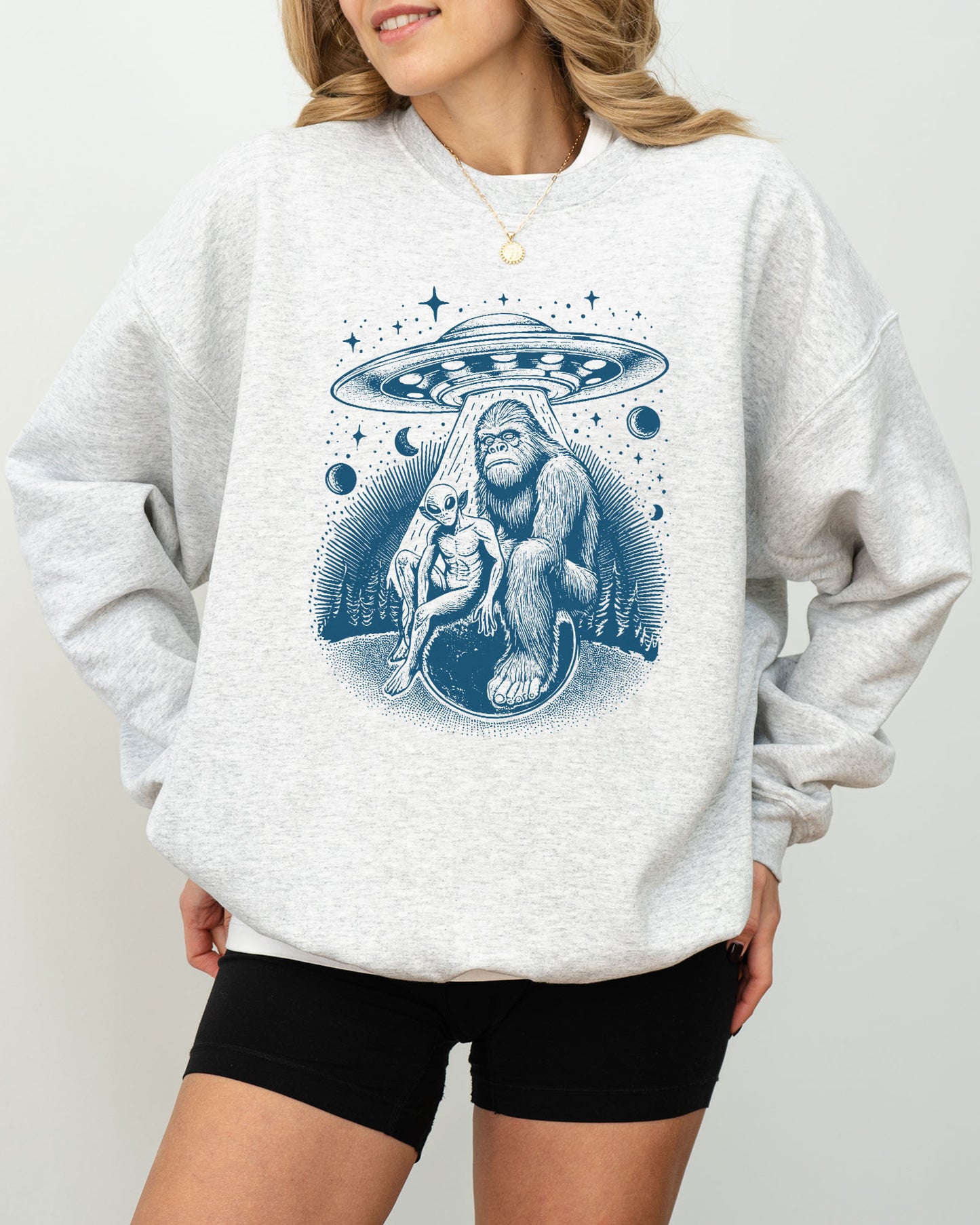 Model wearing ash color sweatshirt with 'Bigfoot, Alien And UFO' graphic design