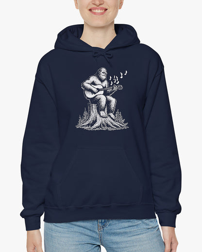 Woman wearing navy blue hoodie with funny retro Bigfoot playing guitar graphic