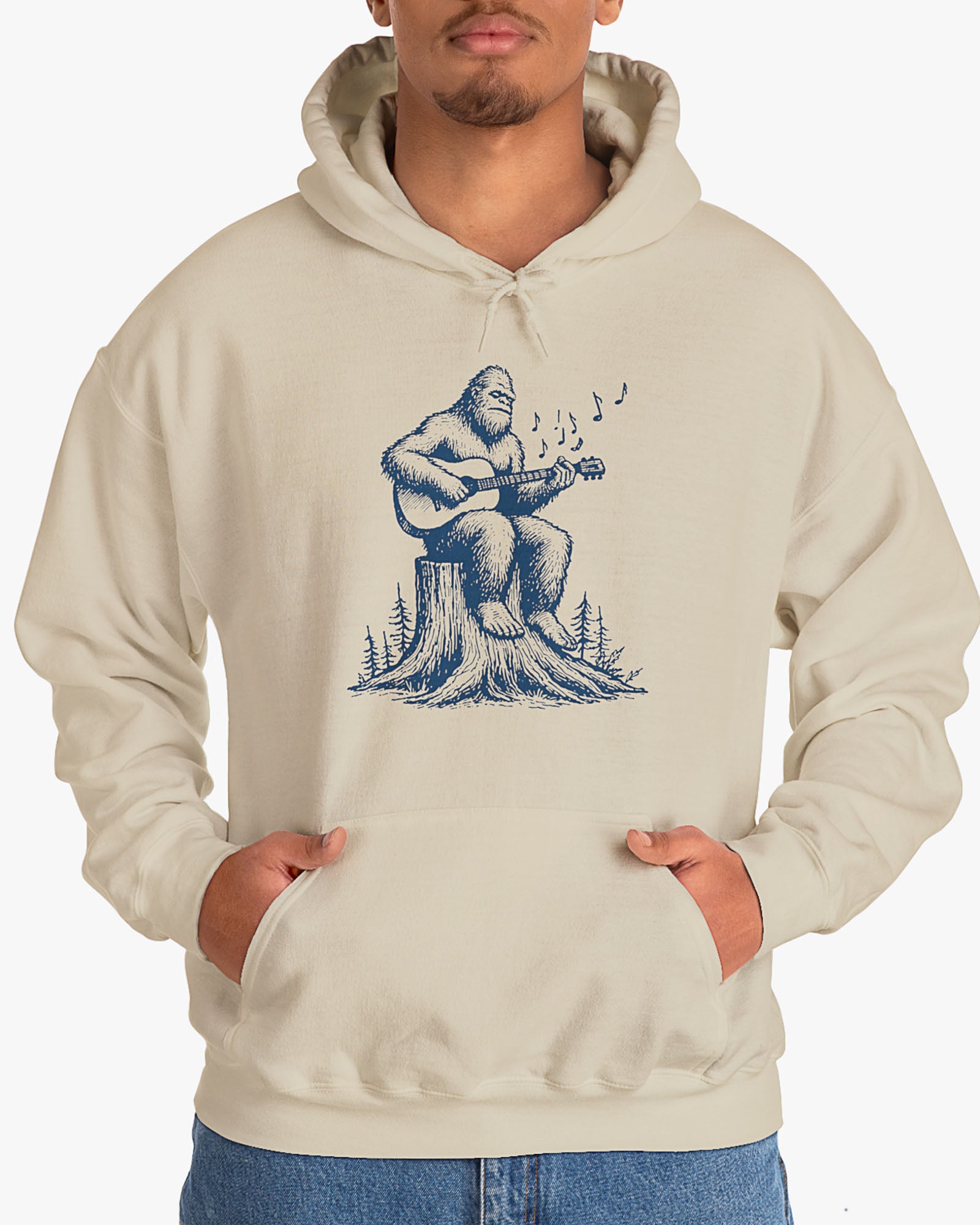 Man wearing sand beige hoodie with funny retro Bigfoot playing guitar graphic
