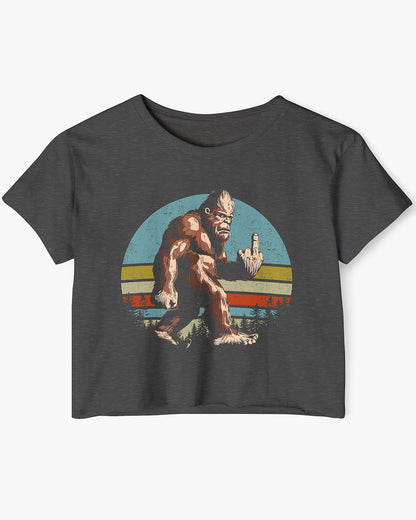 Flat lay of a charcoal crop top with a funny retro-style Bigfoot flipping the middle finger graphic.