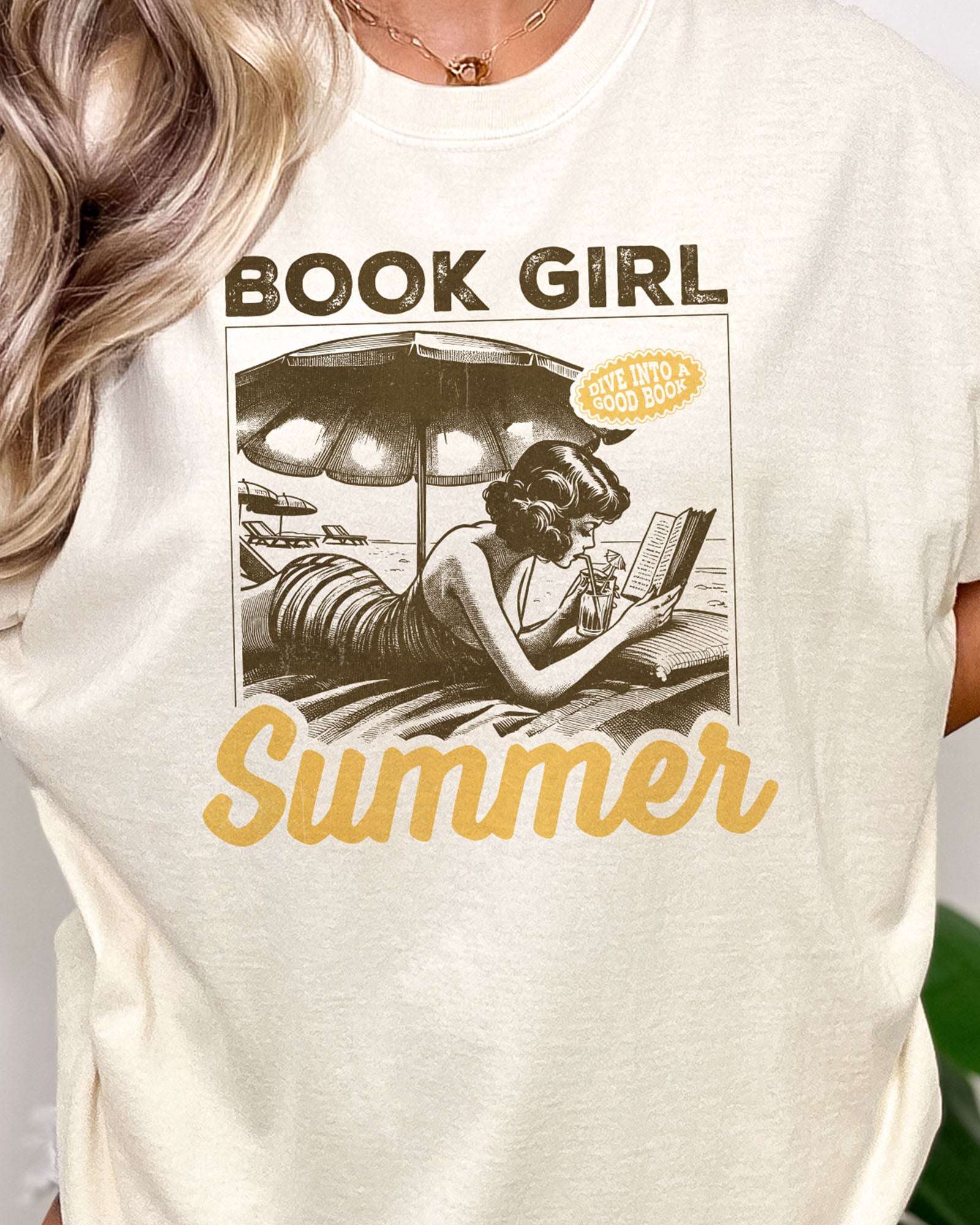 Close-up of woman wearing "Book Girl Summer" t-shirt in ivory color and with a retro graphic of a woman reading on a beach.
