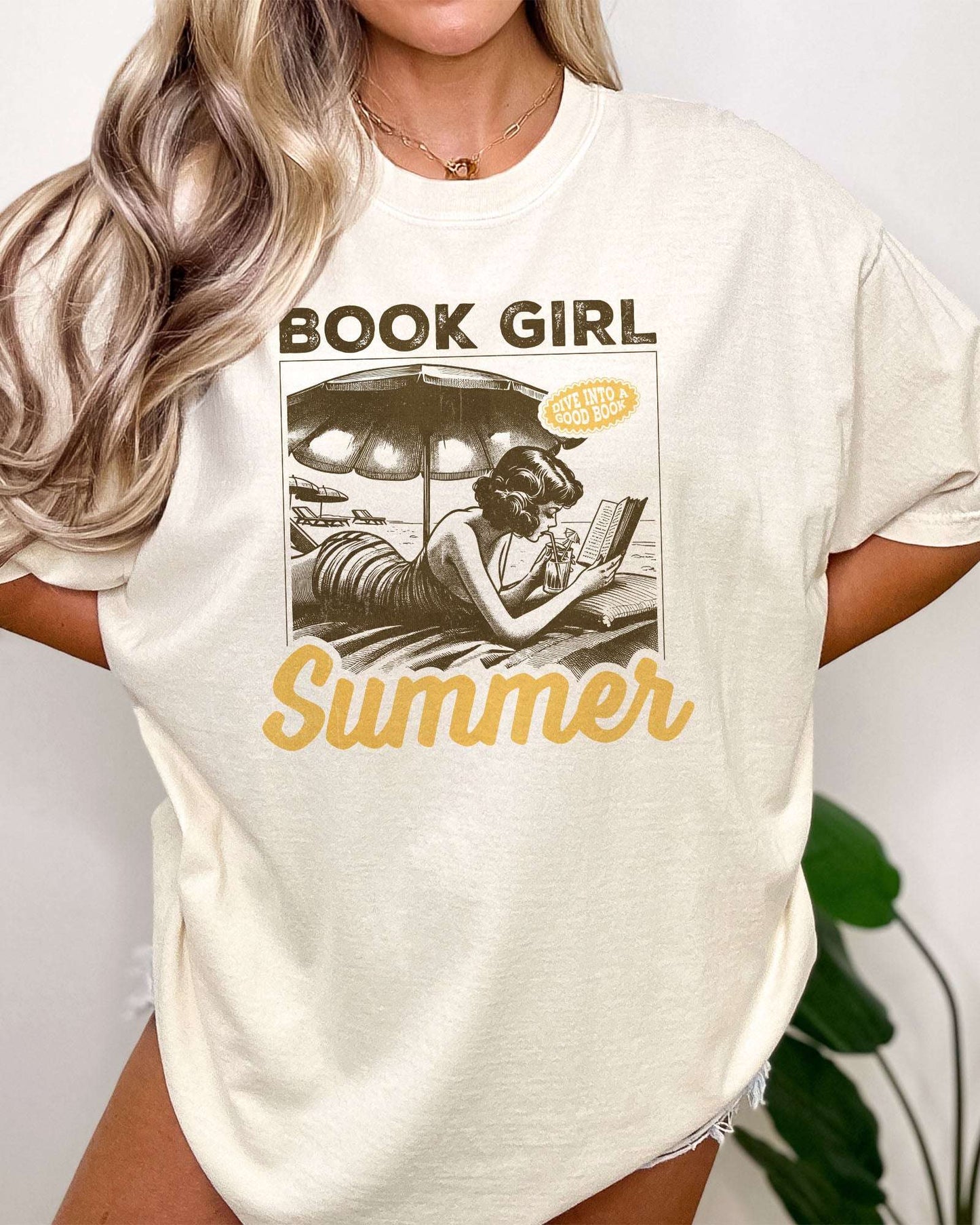 Woman wearing "Book Girl Summer" t-shirt in ivory color and with a retro graphic of a woman reading on a beach.