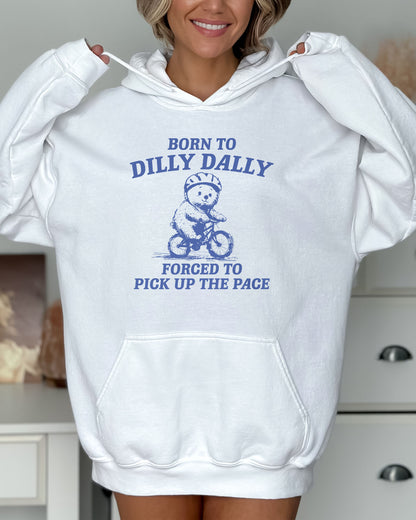 Woman wearing a white hoodie featuring a vintage-style bear riding a bike graphic with the quote 'Born To Dilly Dally, Forced To Pick Up The Pace'.