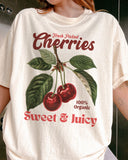 Close-up of woman wearing an ivory "Cherries - Sweet & Juicy" shirt with a retro cherry graphic.