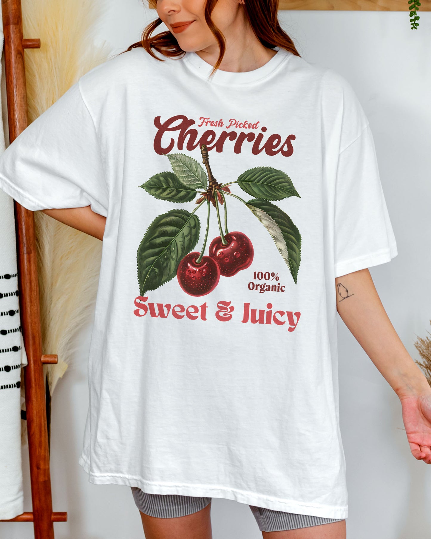 Woman wearing a white "Cherries - Sweet & Juicy" shirt with a retro cherry graphic.