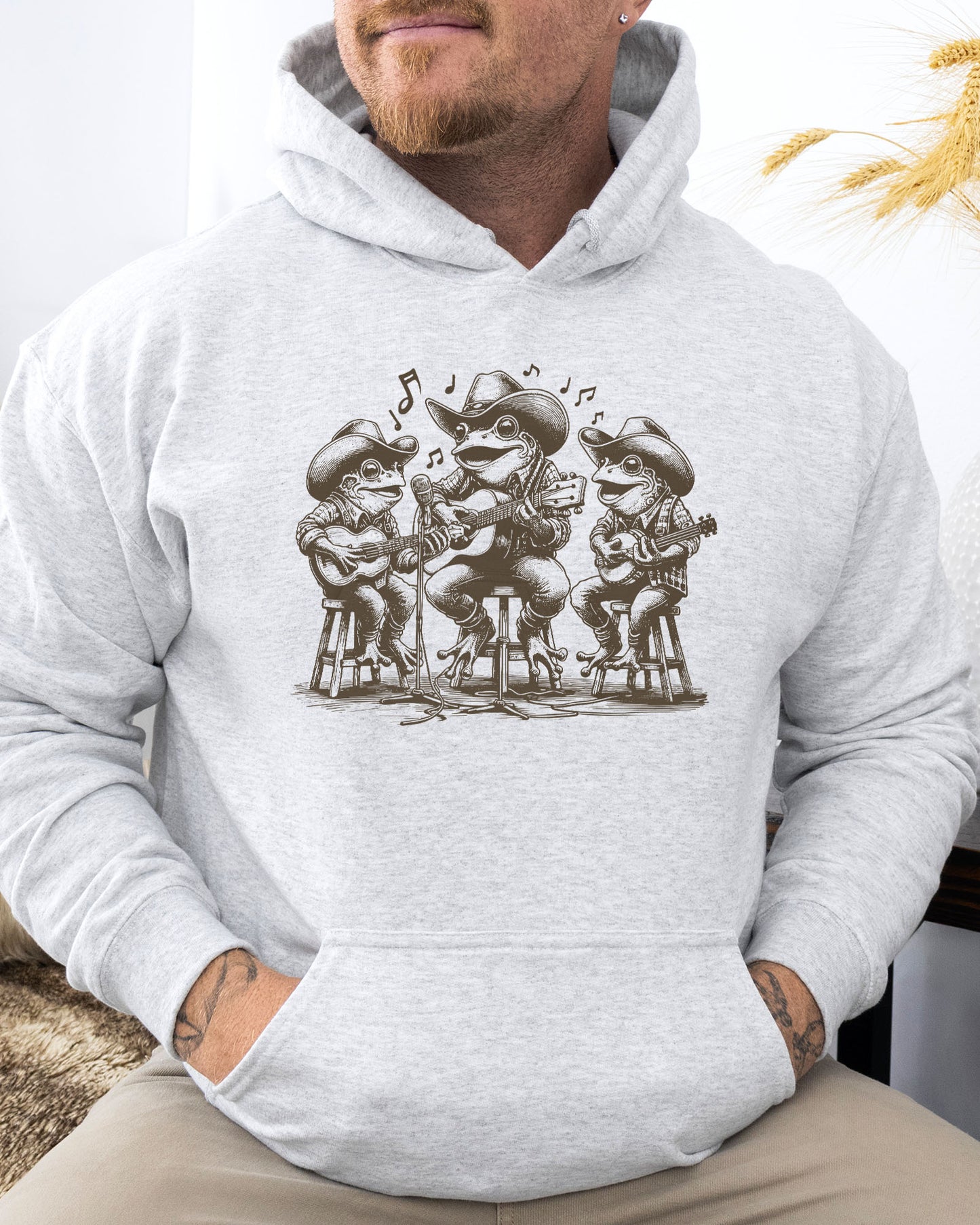 Man wearing ash-colored hoodie featuring a funny retro country frog band graphic.