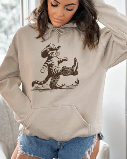 Woman wearing a sand beige hoodie featuring a retro-style cowboy cat graphic with a funny Western theme.