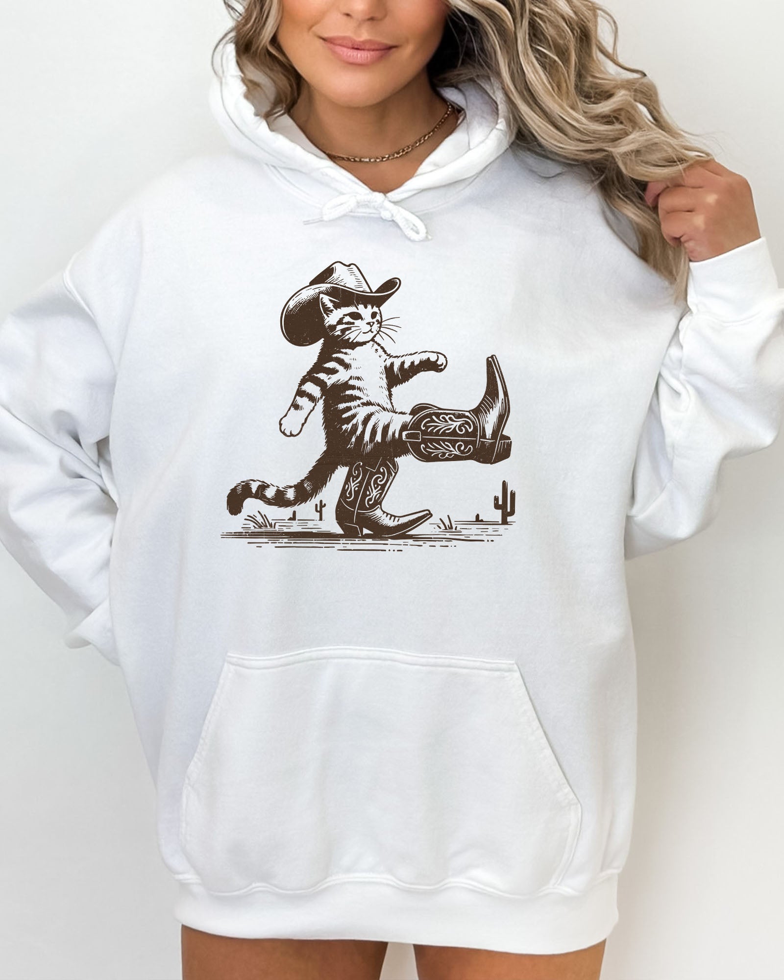 Woman wearing a white hoodie featuring a retro-style cowboy cat graphic with a funny Western theme.