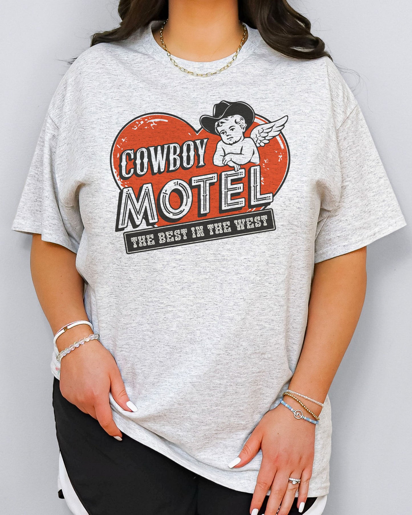 Model wearing ash color shirt with 'Cowboy Motel - The Best In The West' Valentine's Day graphic design