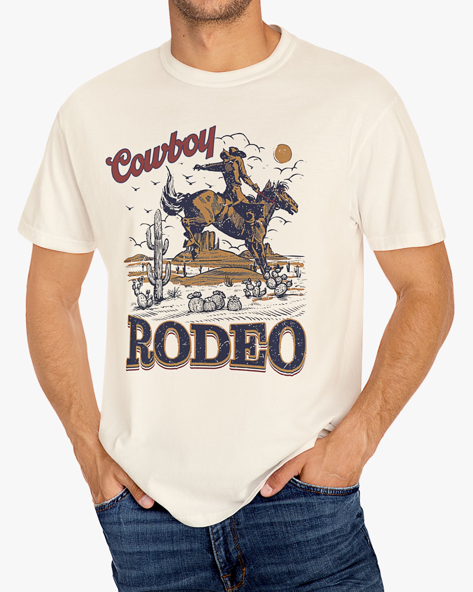 Man wearing a natural beige Cowboy Rodeo graphic t-shirt featuring a retro Western design, standing outdoors.