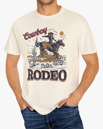Man wearing a natural beige Cowboy Rodeo graphic t-shirt featuring a retro Western design, standing outdoors.