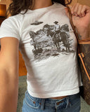 Woman wearing white Y2K baby tee with retro cowboy and UFO graphic