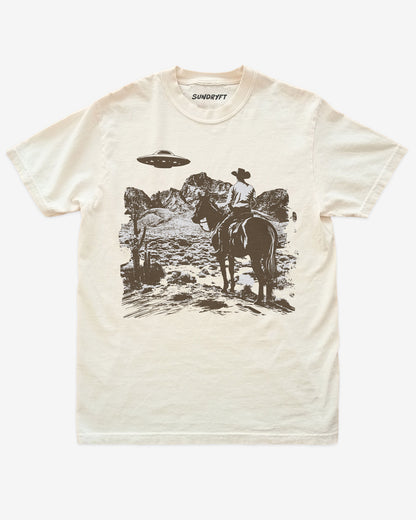 Ivory “Cowboy UFO” shirt with cowboy riding horse through desert under UFO graphic flat lay.