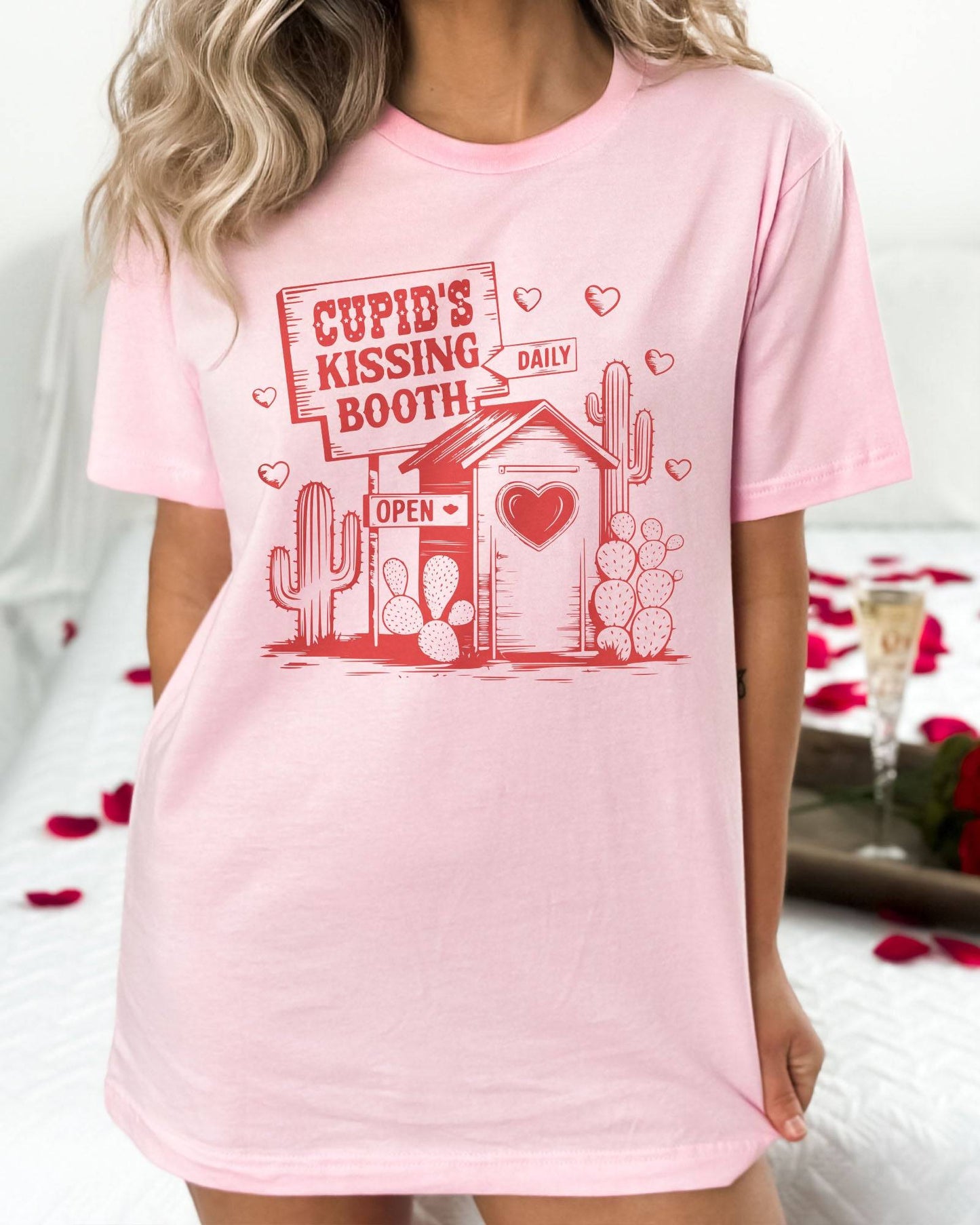 Model wearing light pink color shirt with 'Cupid's Kissing Booth' graphic design
