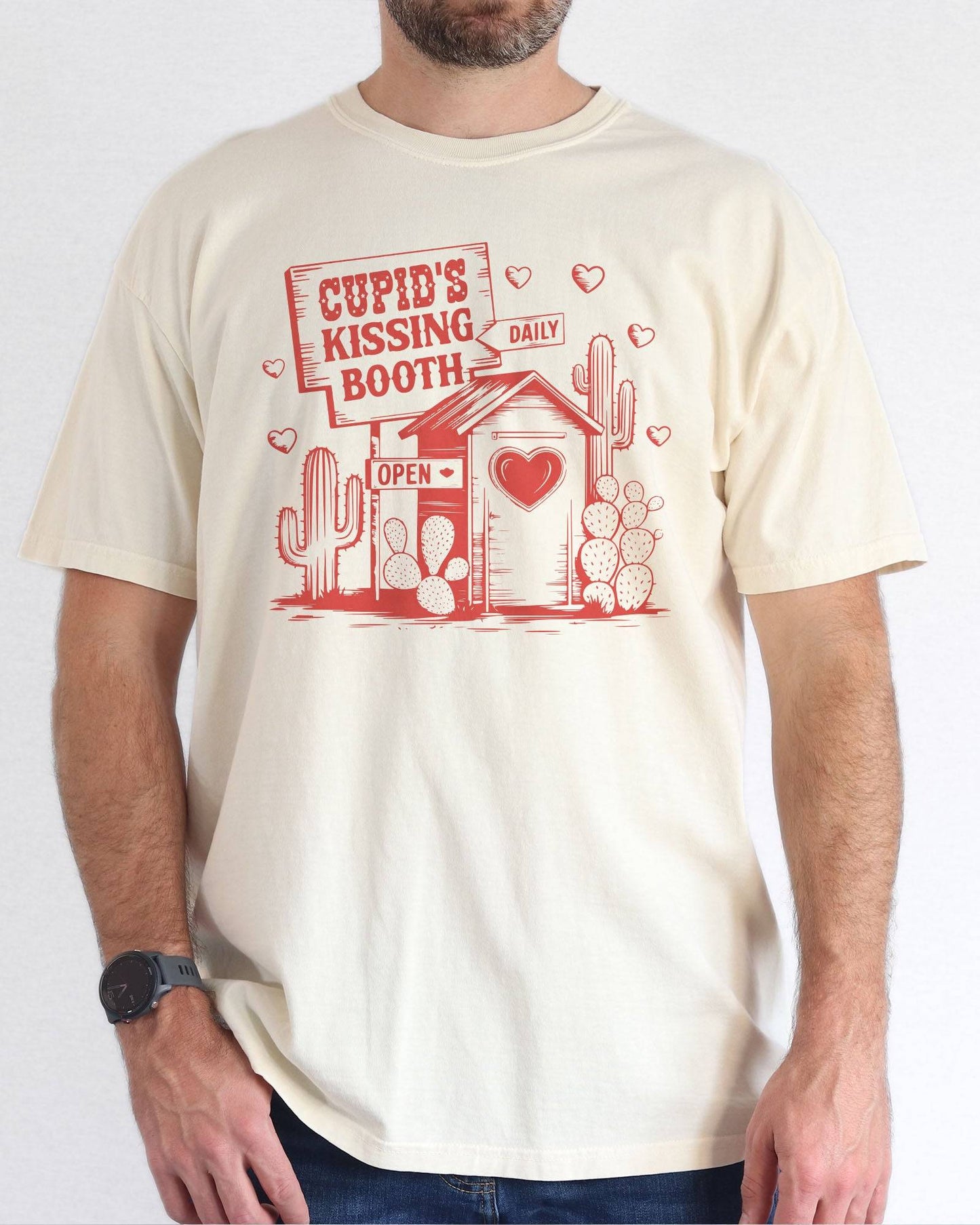 Model wearing natural color shirt with 'Cupid's Kissing Booth' graphic design