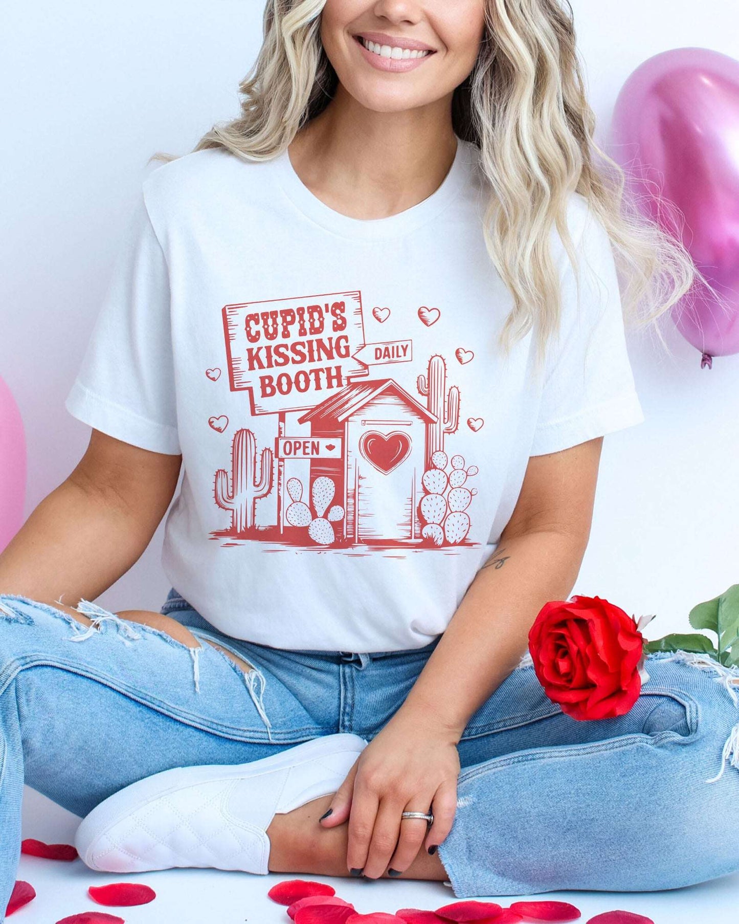 Model wearing white color shirt with 'Cupid's Kissing Booth' graphic design