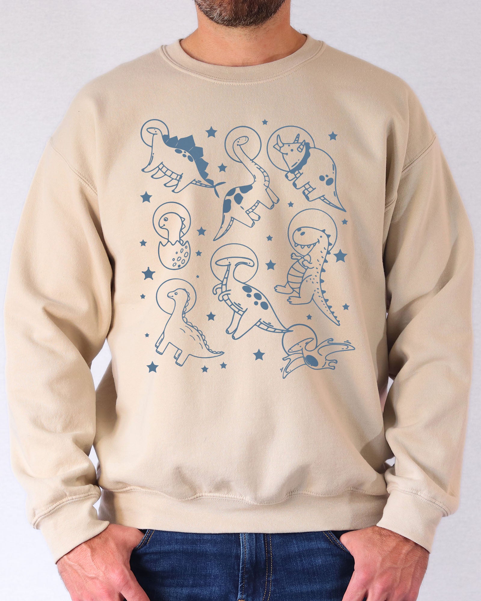 Model wearing sand color sweatshirt with 'Dinosaurs In Space' graphic design