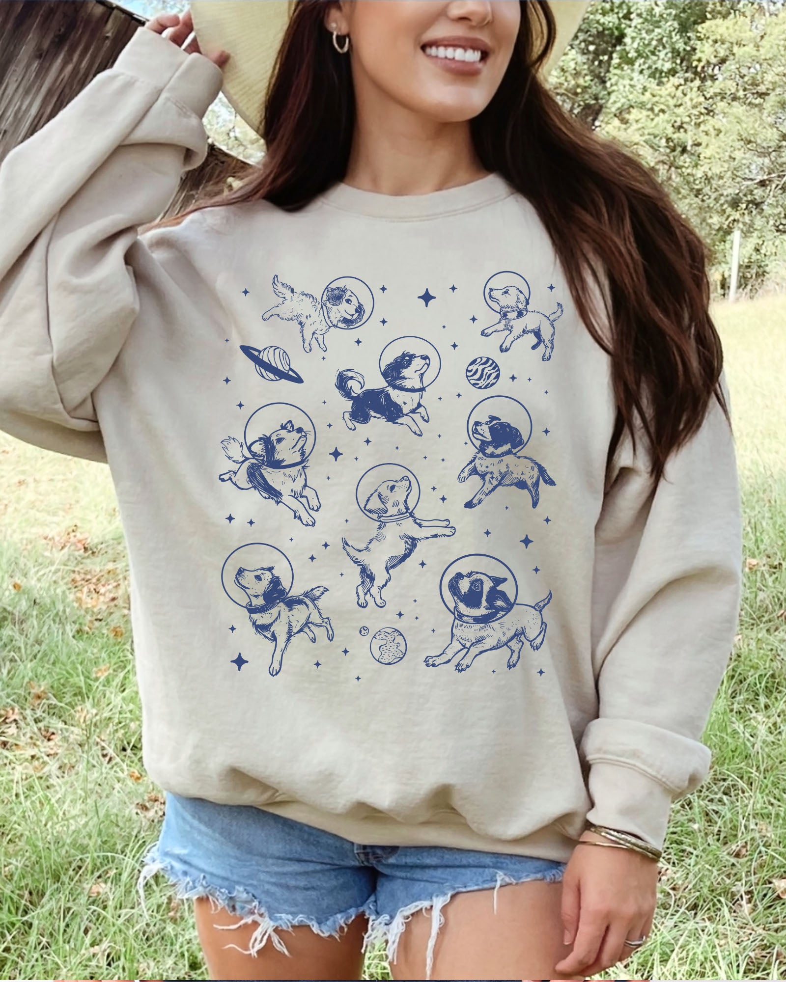 Model wearing sand color sweatshirt with 'Dogs In Space' graphic design