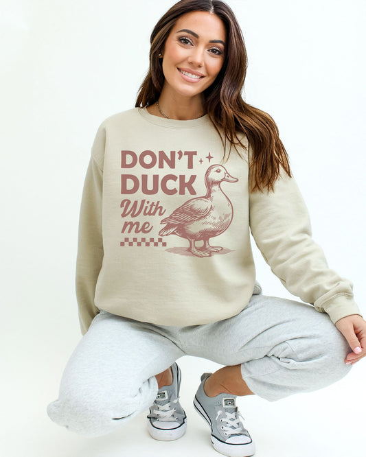 Woman wearing a sand beige sweatshirt featuring a funny retro duck graphic and the quote 'Don't Duck With Me'.