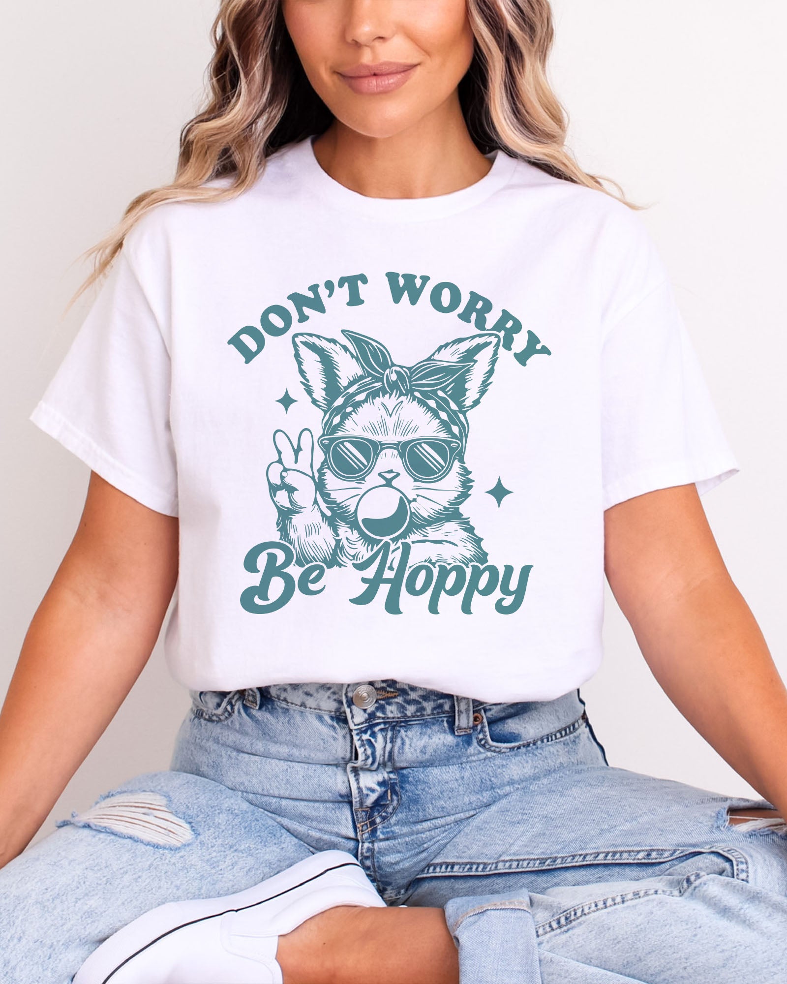 Woman wearing white-colored 'Don't Worry, Be Hoppy' shirt featuring a funny retro easter bunny graphic.