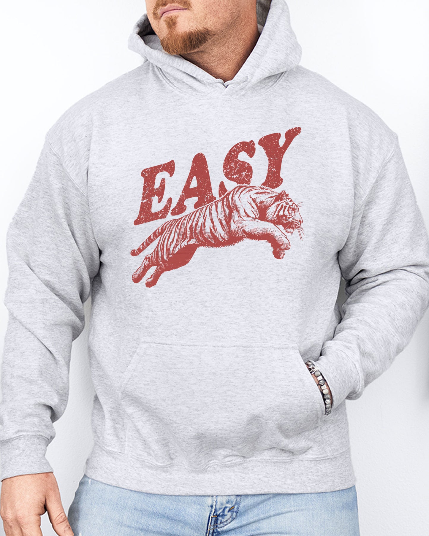 Man wearing an ash-colored 'Easy Tiger' hoodie featuring a vintage-style graphic of a tiger mid-jump.