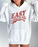 Woman wearing a white-colored 'Easy Tiger' hoodie featuring a vintage-style graphic of a tiger mid-jump.