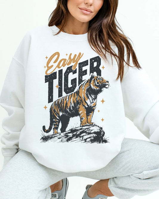 Woman wearing a white sweatshirt with a retro tiger graphic and the funny quote "Easy Tiger" in distressed bold lettering.