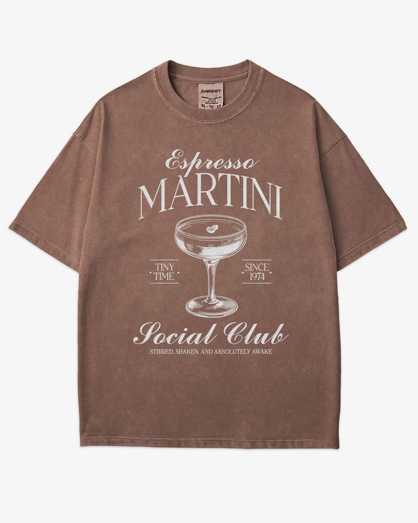 Flat lay espresso-colored 'Espresso Martini Social Club – Stirred, Shaken, and Awake' shirt with a retro graphic of an espresso martini glass.