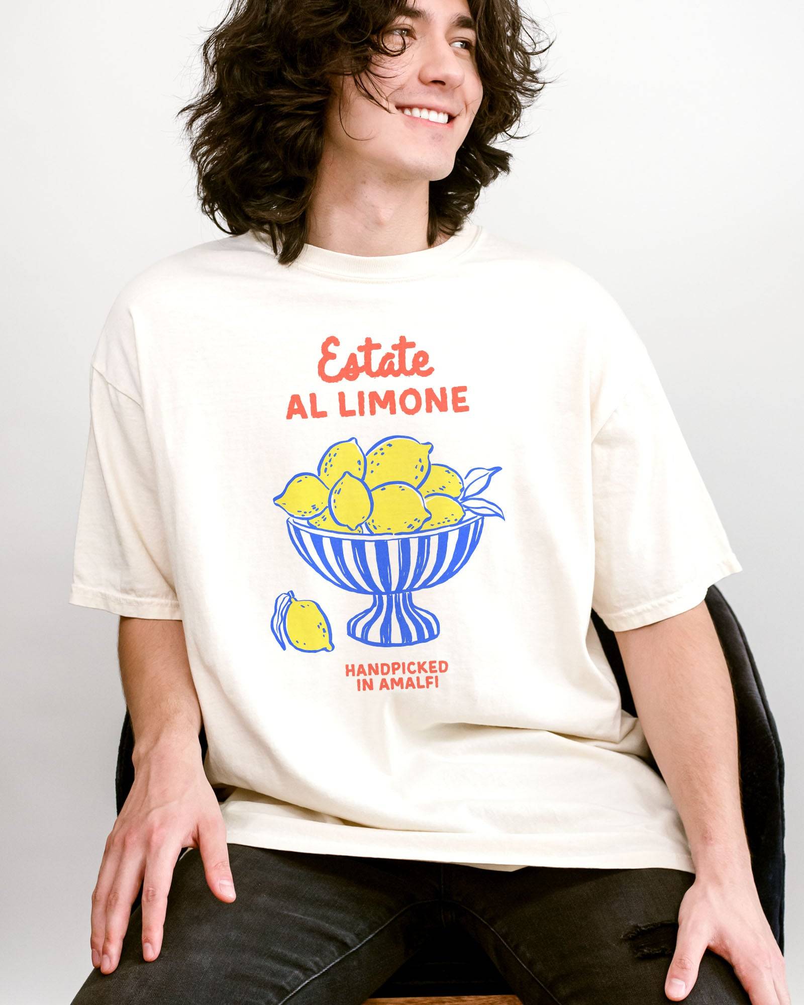 Man wearing an ivory “Estate Al Limone - Handpicked in Amalfi” shirt with a retro graphic of a fruit bowl filled with lemons.